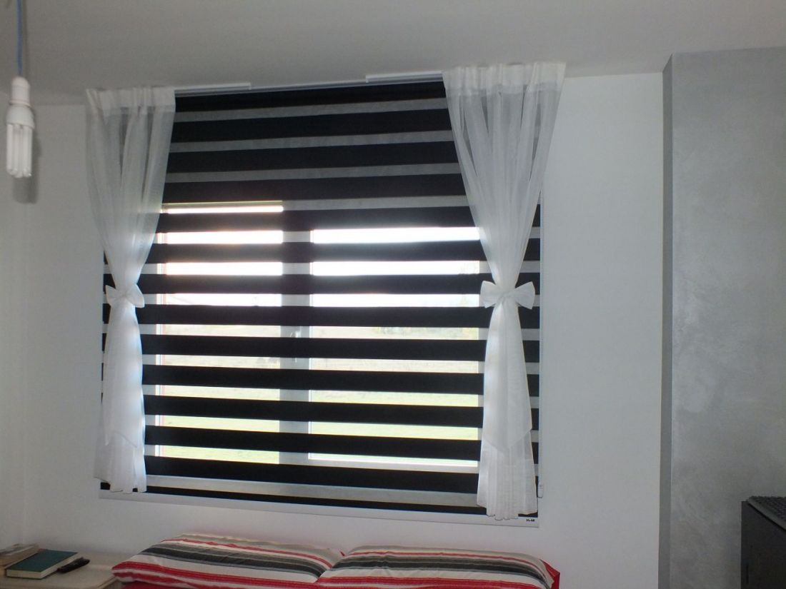 Estor Noche y Día Bandalux color negro con caídas de tela en color blanco en un dormitorio